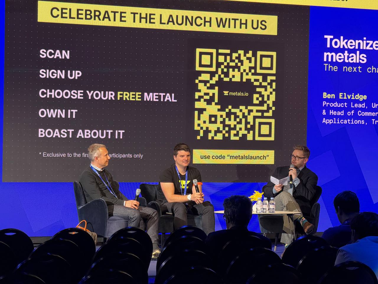 Three-panelist fireside chat on stage at TezDev 2026 in front of the Metals.io launch screen with Giorgio Alessandro Donà-Danioni, Ben Elvidge, and Alexander Tkachenko